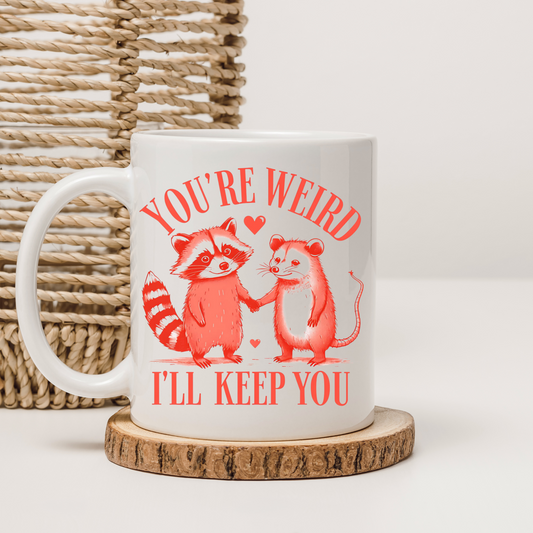 Cute 'You're Weird, I'll Keep You' mug with raccoon and mouse illustration – Perfect gift for quirky friends.